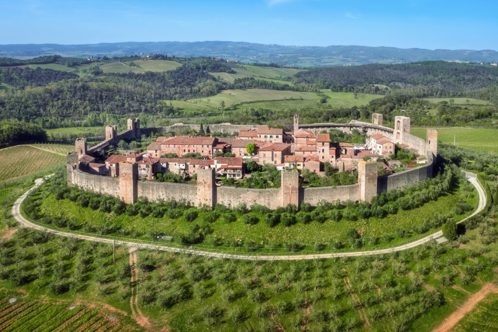 Monteriggioni otaczają średniowieczne mury z basztami, widoczne z daleka wśród winnic i gajów oliwnych.