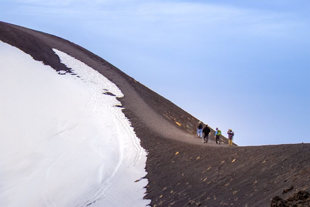 Trekking na Etnę prowadzi po zboczach z czarnego piasku wulkanicznego, a wiosną jeszcze po śniegu.