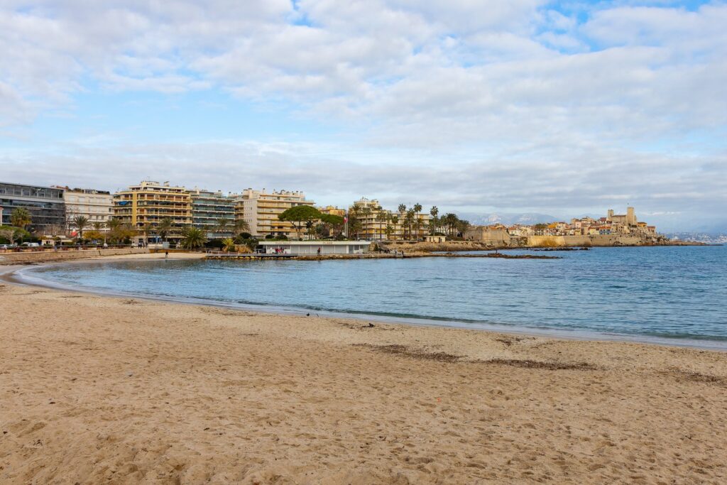 Z piaszczystej plaży w Juan-les-Pins widać w oddali stare miasto Antibes